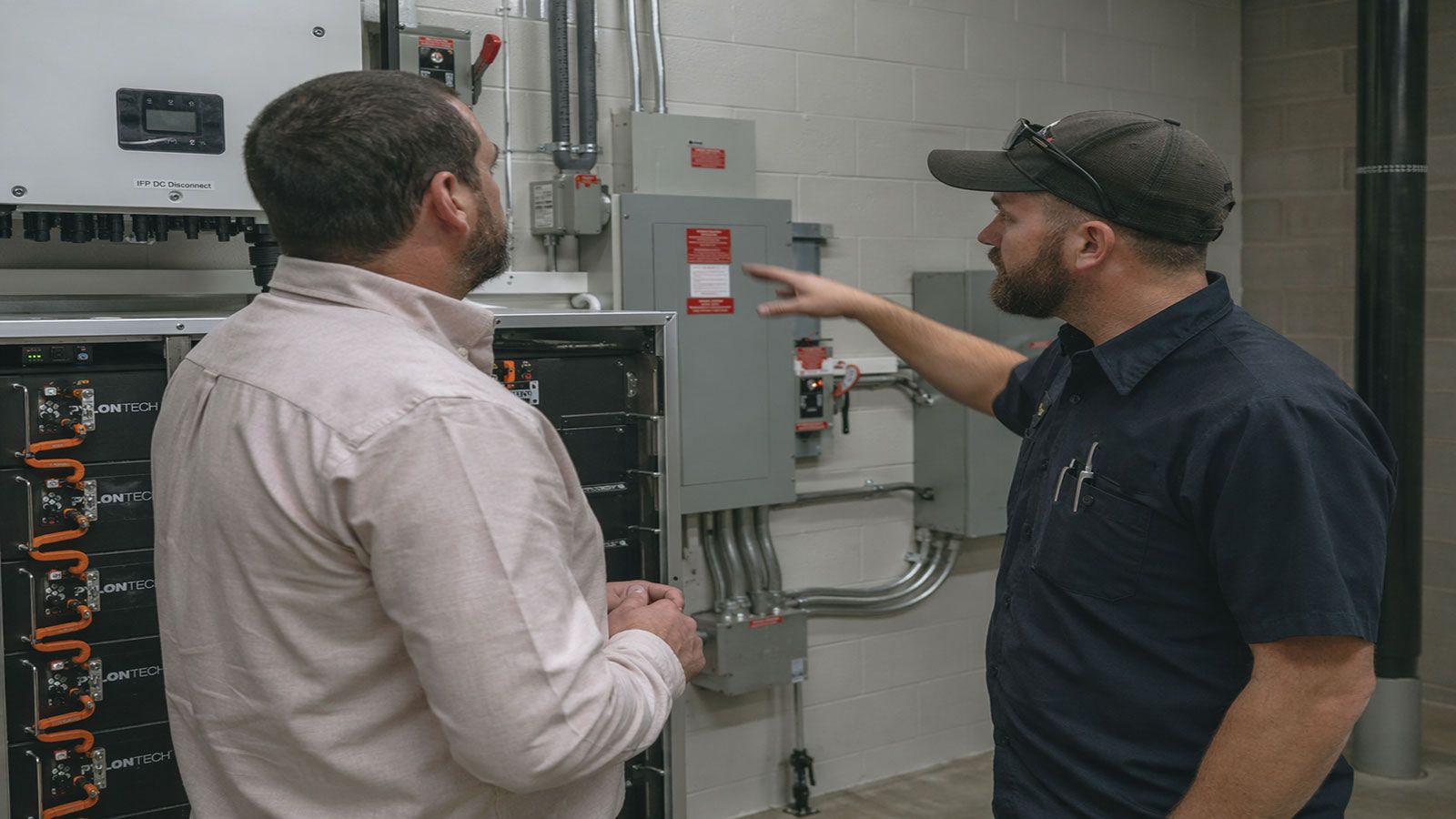 Τεχνικός ενημερώνει επαγγελματία για εγκατάσταση συστήματος αποθήκευσης ενέργειας.